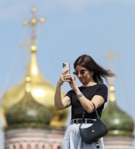امرأة تلتقط صورة في حديقة زاريادي، وخلفها قباب كنيسة، بموسكو، روسيا.   «رويترز»